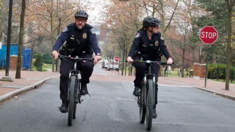 Two officers on bikes traveling on road on campus.