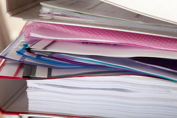 Stack of paper documents, binders, and folders.