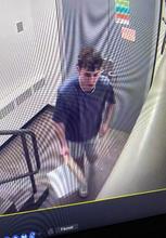 Camera image of mail individual leaving Wolf Hall with damaged Exit sign